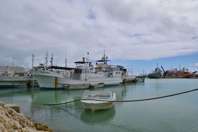 Sailboats moored at harbor against sky