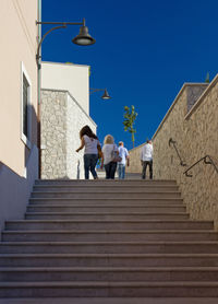 Low angle view of people walking on staircase against building