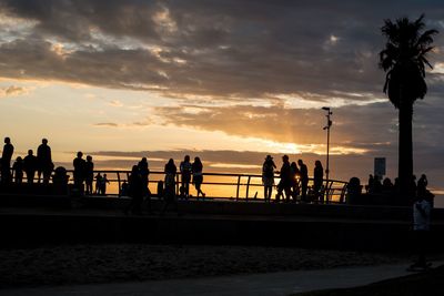 Silhouette people at observation point against cloudy sky during sunset