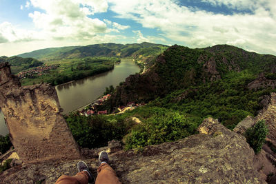 Low section of person by river against mountains
