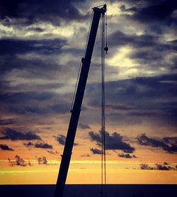 Low angle view of silhouette crane against sky during sunset