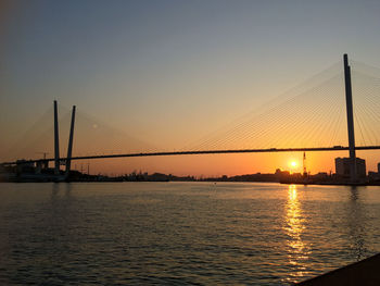 View of suspension bridge over river at sunset