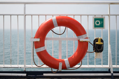 Orange life belt on railing against sea