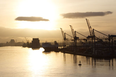 Silhouette of harbor against sky during sunset