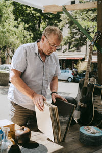 Senior man choosing records standing near stall at flea market