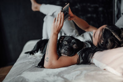 Midsection of woman with dog lying on bed