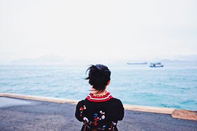 Rear view of woman on beach against clear sky