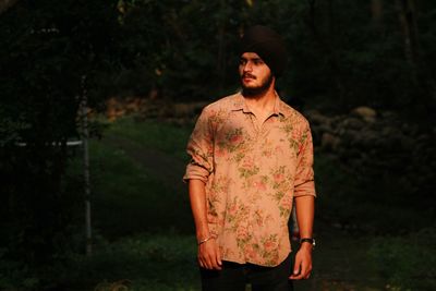 Young man looking away while standing on land