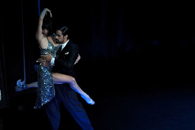 Full length of young couple kissing against black background