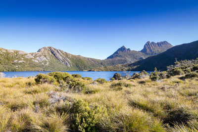 Scenic view of lake and mountains against clear blue sky