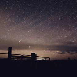 Silhouette railing against sky at night