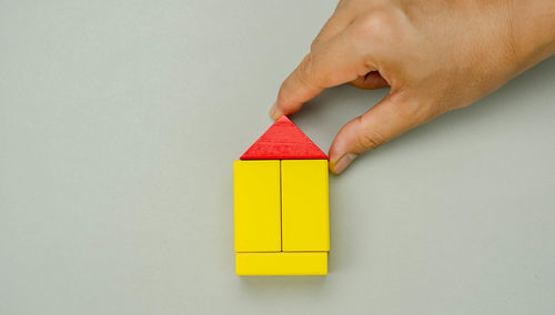 Close-up of hand holding toy against white background