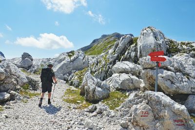 Rear view of man walking on rock against sky