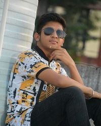 Midsection of young man wearing sunglasses sitting outdoors