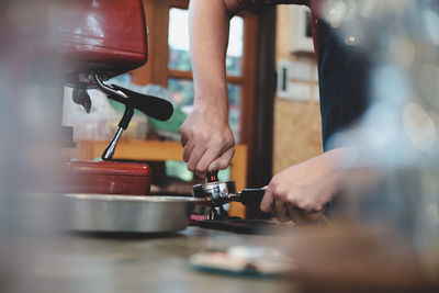 Midsection of barista preparing coffee in kitchen