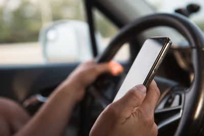 Close-up of man using mobile phone while driving car