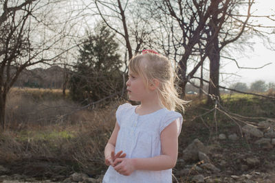 Thoughtful girl standing against bare trees