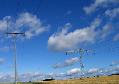 Low angle view of electricity pylon against cloudy sky