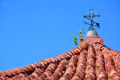 Low angle view of cross on roof of building against clear blue sky