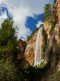 Low angle view of waterfall against sky