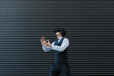 Side view of young man standing against wall