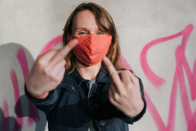 Portrait of beautiful woman standing against graffiti wall