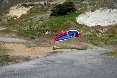Man paragliding over road against mountain