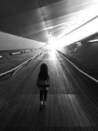 Rear view of woman standing on illuminated road