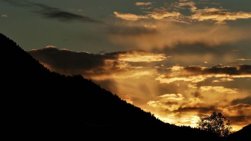 Silhouette trees against dramatic sky during sunset