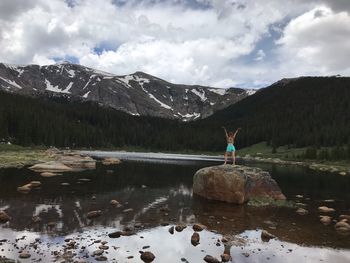 Woman standing on rock in lake against sky