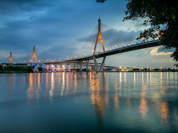 Low angle view of bridge over river against cloudy sky during sunset