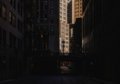 Illuminated street amidst buildings in city 