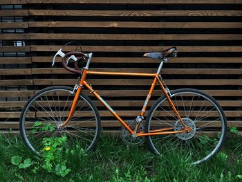 Bicycle parked on grassy field by log cabin