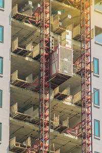 Low angle view of cranes against buildings