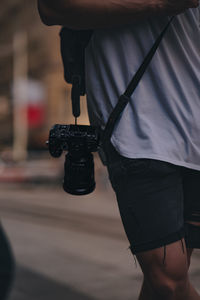 Midsection of man holding his camera with strap