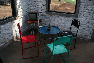 High angle view of empty chairs and table against wall