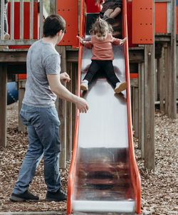 A man with a girl on the playground in the park.