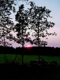 Silhouette trees on field against sky during sunset