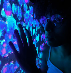 Close-up of woman by illuminated wall