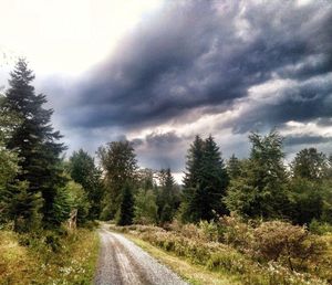 Road passing through landscape against cloudy sky