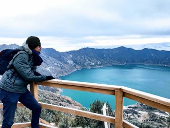 Man standing by railing against mountain and sky