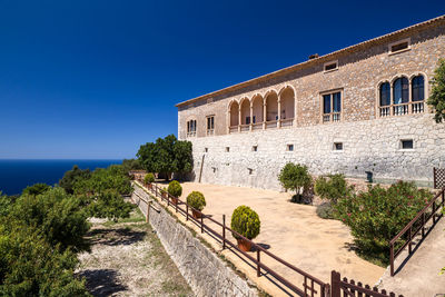 Building by sea against clear blue sky