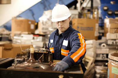 Male worker checking electrical equipment in recycling plant