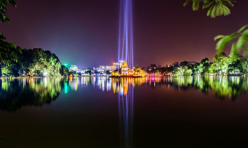 Reflection of illuminated trees in lake at night