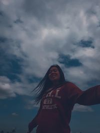 Low angle view of smiling woman standing against sky