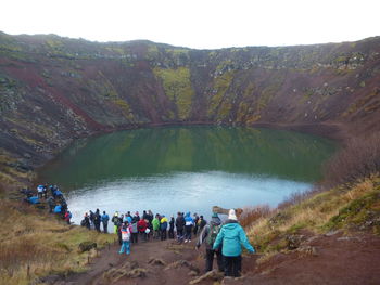 People standing on mountain by lake