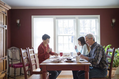 Happy family eating breakfast at table in home