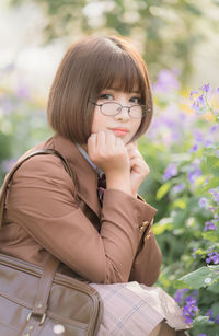 Portrait of woman sitting by plants at park