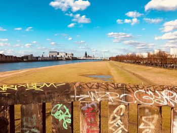 Graffiti on wooden fence against river in city