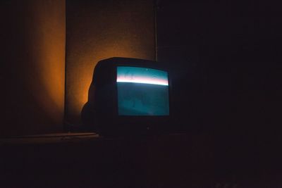 Illuminated light bulb against wall in dark room